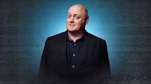 Dara Ó Briain posant sous fond vert marin