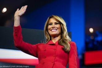 Femme en rouge saluant la foule.